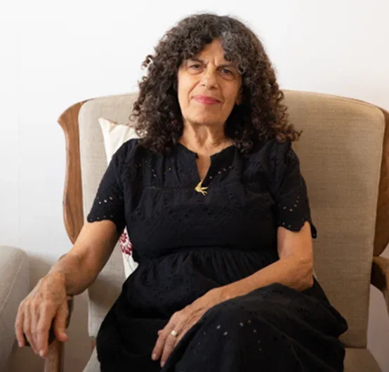 מיריק שניר יושבת בכורסה בביתה